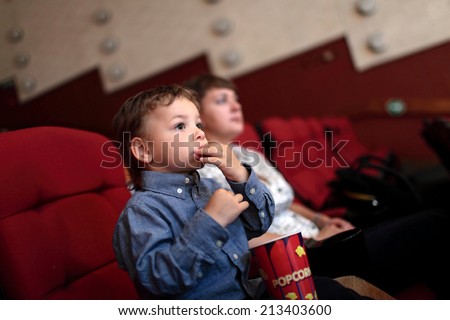 The boy eating popcorn in the cinema