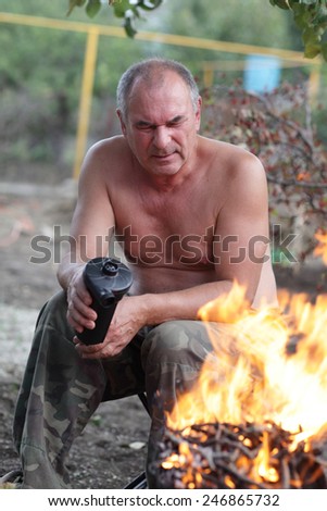 Man fanning the fire in the barbecue grill at backyard