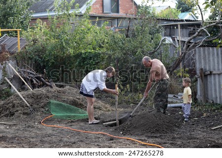 Family planting seedlings of fruit trees in ground