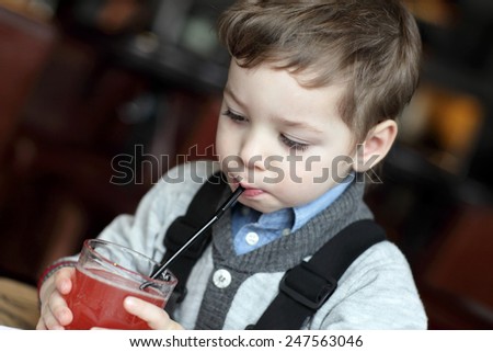 Kid drinking red juice in the cafe
