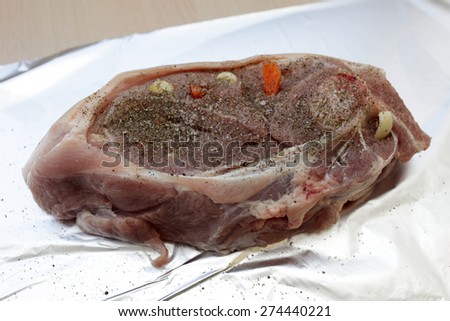 Raw pork shoulder larded with carrots on a foil