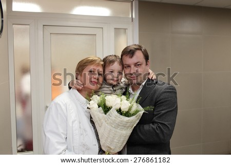 Family posing with bunch of flowers indoor