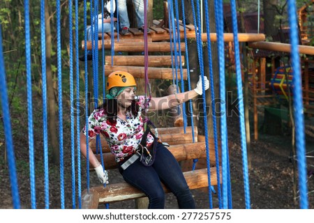 Woman climber resting on a log in the adventure park