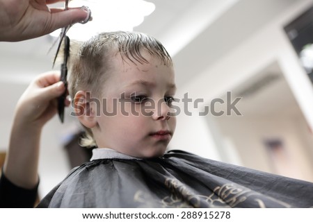 Barber cutting hair of a kid at the barbershop