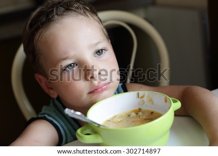 Thinking child with plate of soup at home
