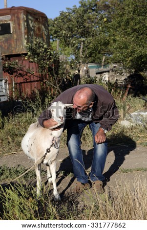 Senior man with a goat on the farm