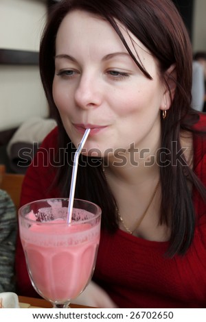 The woman drinks strawberry milk shake in a cafe