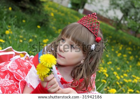 The girl in red dress with dandelions on lawn