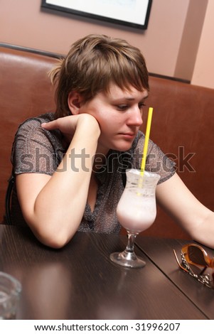 Sad woman drinks milk shake in a cafe