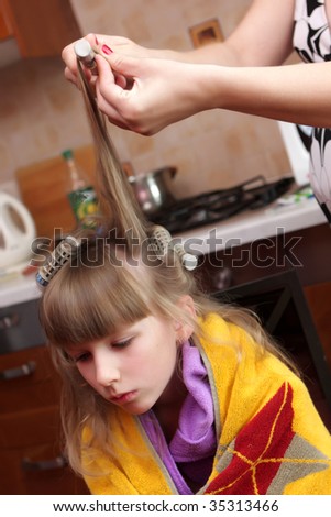 A woman winds the treated section\'s hair into the heated rollers
