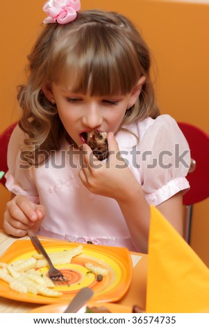 The hungry girl eats meat in a cafe