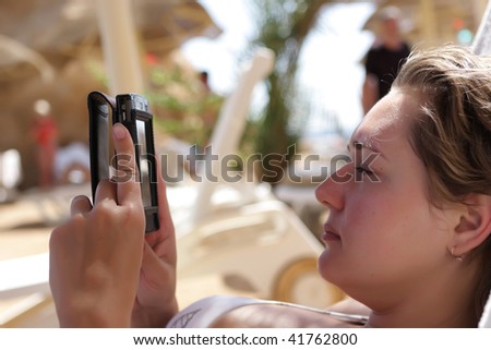 A woman reading a book by pocket PC on a beach