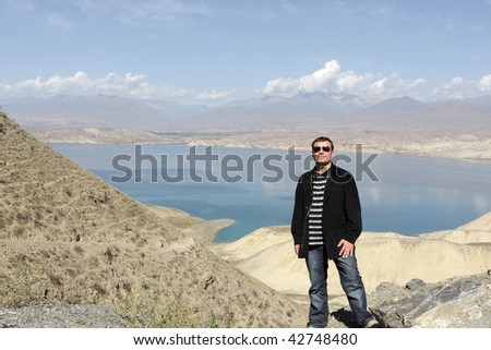 Portrait of man on Toktogul Reservoir background, located in the Jalal-Abad Province of Kyrgyzstan, is the largest of the reservoirs on the path of the Naryn River. Bishkek - Osh road