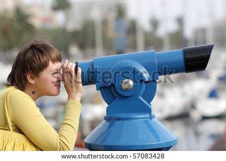 The woman looks through telescope on city