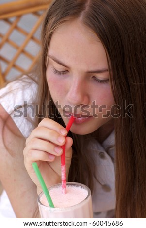 The teen drinks milk strawberry shake at the cafe