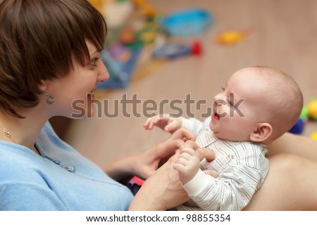 The mother tickles her baby boy at home