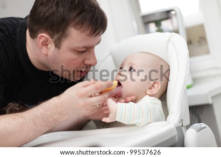 The father feeding his baby in a highchair at home
