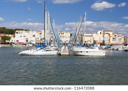 Marina of Gruissan in south france with landing stage and many sailing boats with vacation rentals in the background