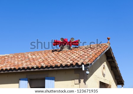 Big red fire siren on house roof against a blue sky