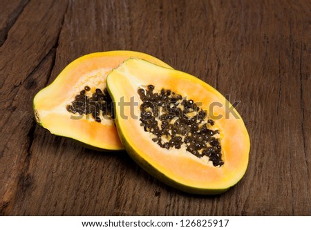 Halved papaya fruit is on an old solid wood table