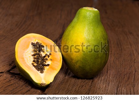 Halved papaya fruit is on an old solid wood table