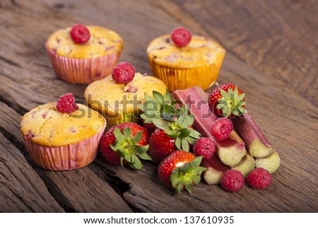 Some whole fruit muffins and fresh and delicious fruits ingredients on a old wooden board