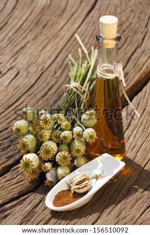 Poppy capsule, poppy seeds and poppy seed oil bottle is standing on an old rustic wooden table