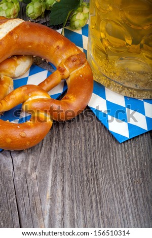 A beer mug and pretzels on napkins with blue and white rhombuses on a rustic wooden table