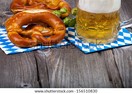 A beer mug and pretzels on napkins with blue and white rhombuses on a rustic wooden table