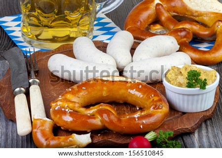 Typical Bavarian Oktoberfest snack with white sausage, mustard, a glass of beer and pretzels on an old rustic wooden table