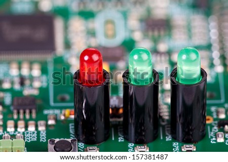 Two green and one red LED in sockets on a circuit board as Close-up view