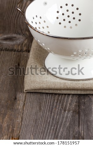 Colander stands on a rustic kitchen table with copy space in the lower area of the image