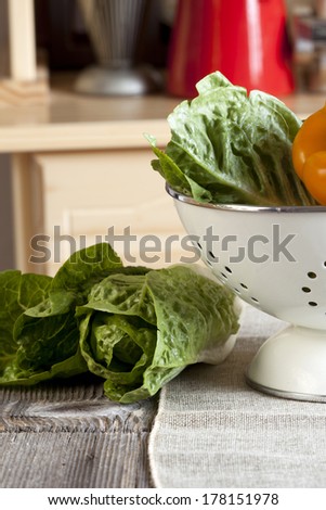 Vegetables in a colander and on the kitchen table in the background a kitchen cupboard