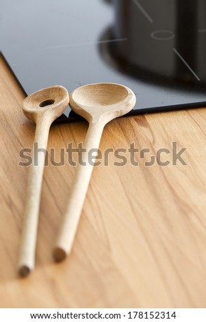 Two Cooking Spoon lies on Worktop nearby Ceramic Hob with Copy Space in the lower Area of the Image