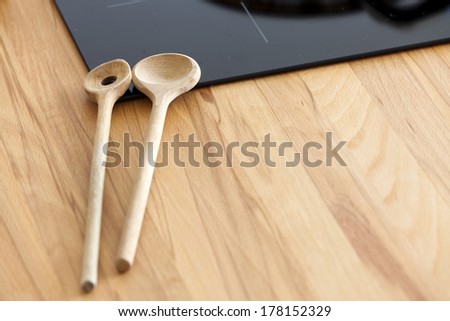 Two Cooking Spoon lies on Worktop nearby Ceramic Hob with Copy Space in the lower Area of the Image