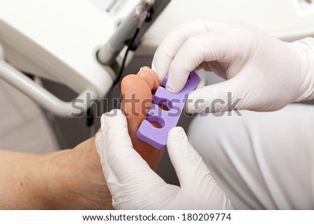 Chiropodists puts a female customer a Toe Divider over the toes