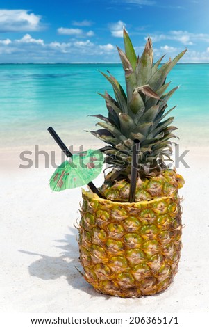 Tropical Pineapple drink in the sand on the beach with the ocean in the background