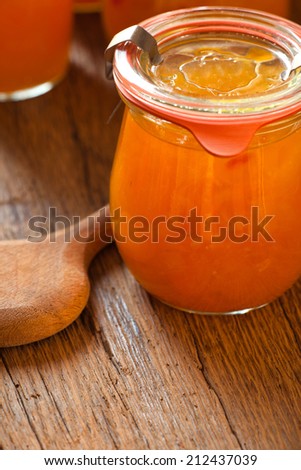 Homemade melon jam in a preserving jar with a wooden spoon on old wooden table