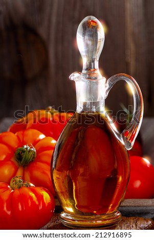 Fresh beef tomatoes and a carafe of olive oil on a old rustic cutting board in country style