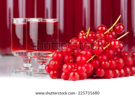 Close-up view of ripe red currants and syrup in a glass and bottles isolated on white background