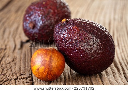 Two ripe avocados and avocado stone on an old rustic wooden plank
