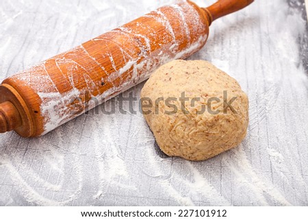 Wooden rolling pin and a dough ball on silicone baking board