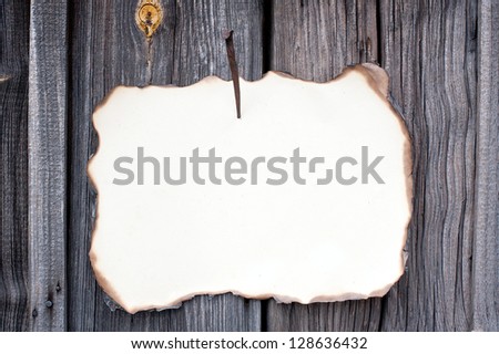 nailed sheet of yellowed burnt paper at wooden wall
