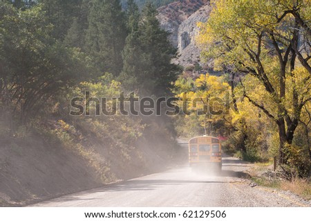 School bus on a rural dirt road in autumn