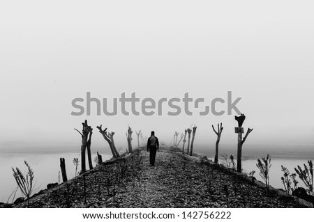 Man walking in a thick fog on wild desolate landscape  Black and white