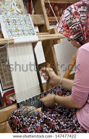Istanbul, TURKEY - August 14: Local woman weaves a carpet by hand on August  14, 2011 in Istanbul, Turkey. This low-tech method has remained unchanged for centuries.