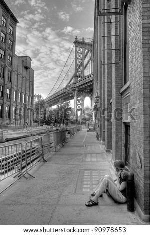 woman on cellphone on brooklyn street at manhattan bridge