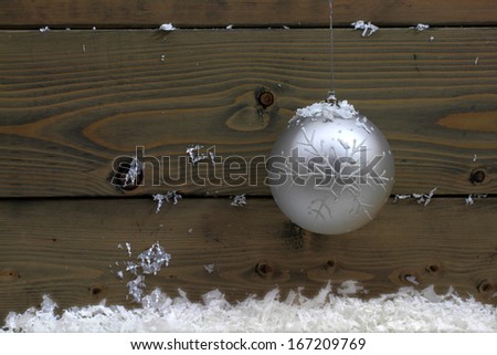 Christmas (New Year, Holiday Season) Decoration (Decorative white ball hang in front of wooden wall over snow) very suitable for Greeting Card (space for text in left part of picture)