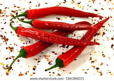 Group of red pepper crimson hot with small diameter over the white background dusted with red crashed hot pepper.