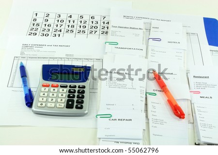 Picture of all expense report forms, daily and monthly, electronic calculator, pens and bills used to finalize financially the month - getting ready to fill down daily and monthly expense reports.